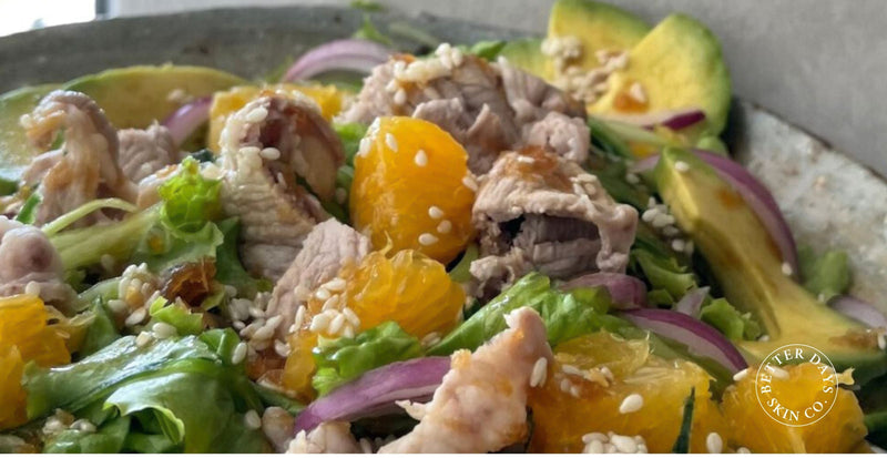 A vibrant Pork Shabu Salad featuring chopped lettuce, sliced avocado, red onion, orange segments, and thinly sliced cucumber, topped with tender shabu pork, beautifully arranged in a bowl.