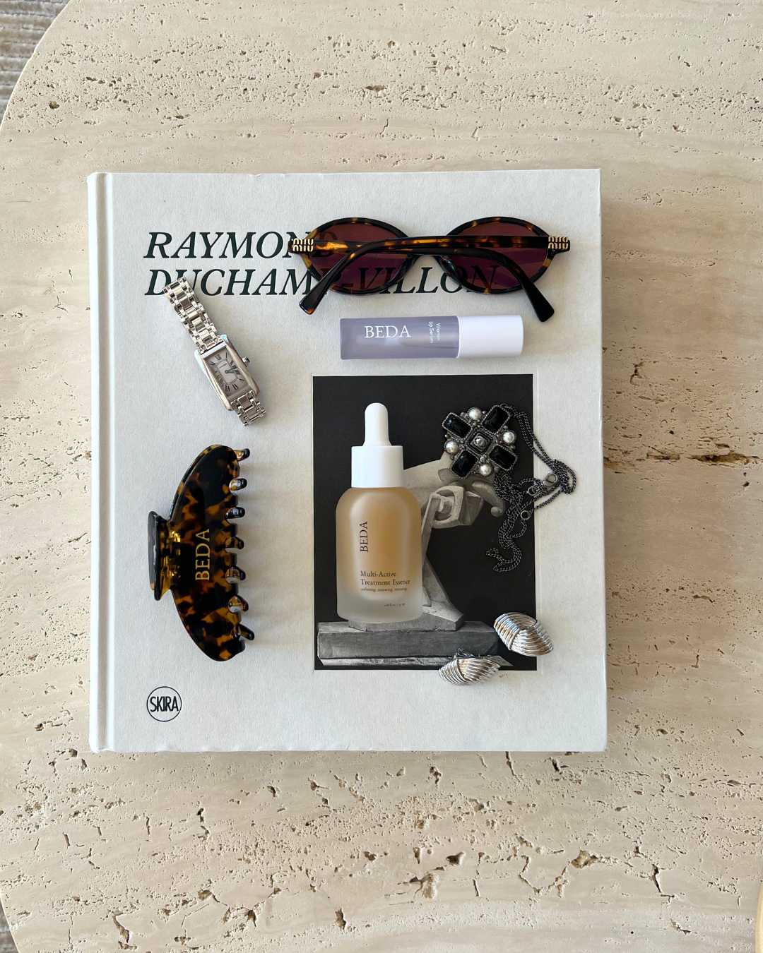 skincare, sunglasses, jewelry on coffee table book aesthetic